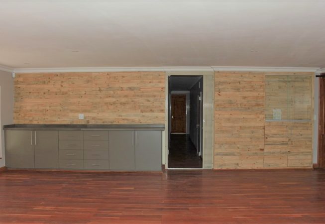 Storm Grey melamine cupboards with recycles pallet wood wall panel and glass display cupboard and poured concrete top