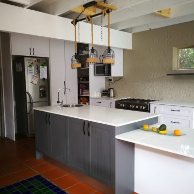 White melamine with white shaker wrap doors and Vanilla quartz tops Island unit in Storm Grey