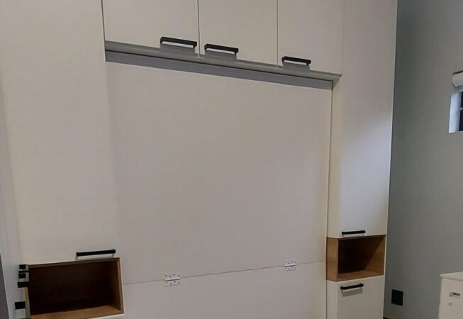 White melamine cupboards and Murphy bed with fold-down desk and built-in bedside tables