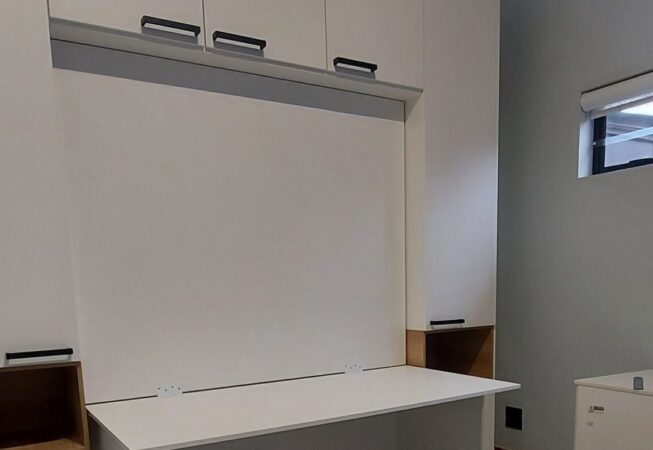 White melamine cupboards and Murphy bed with fold-down desk and built-in bedside tables